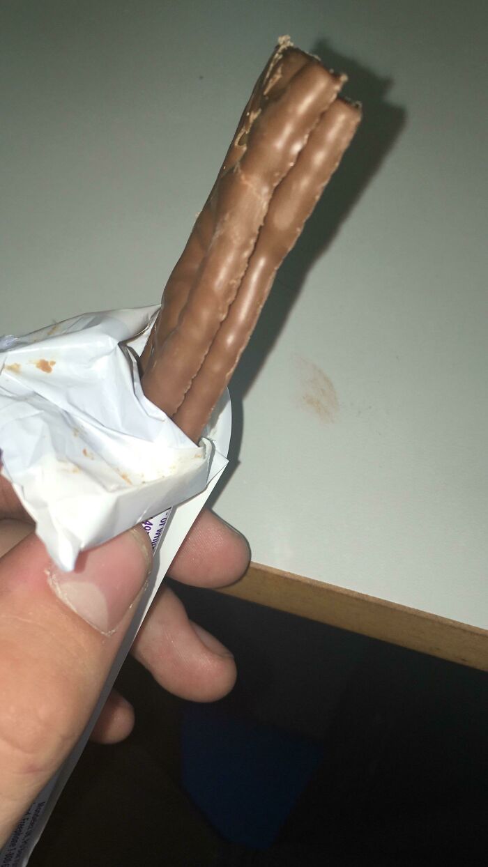 Hand holding a partially unwrapped chocolate bar with two finger-like pieces, reflecting Irish sense of humor posts.