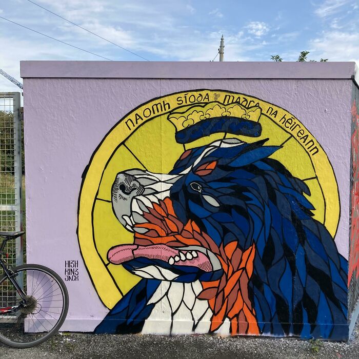 Colorful mural of an Irish dog with tongue out, featuring bold lines and bright colors, representing Irish humor and culture.