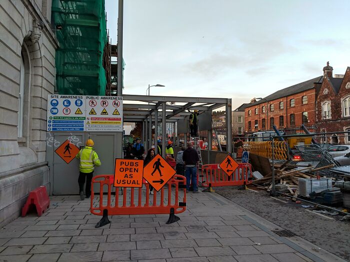 Street construction scene in Ireland with signs humorously stating pubs open as usual, reflecting Irish sense of humor.