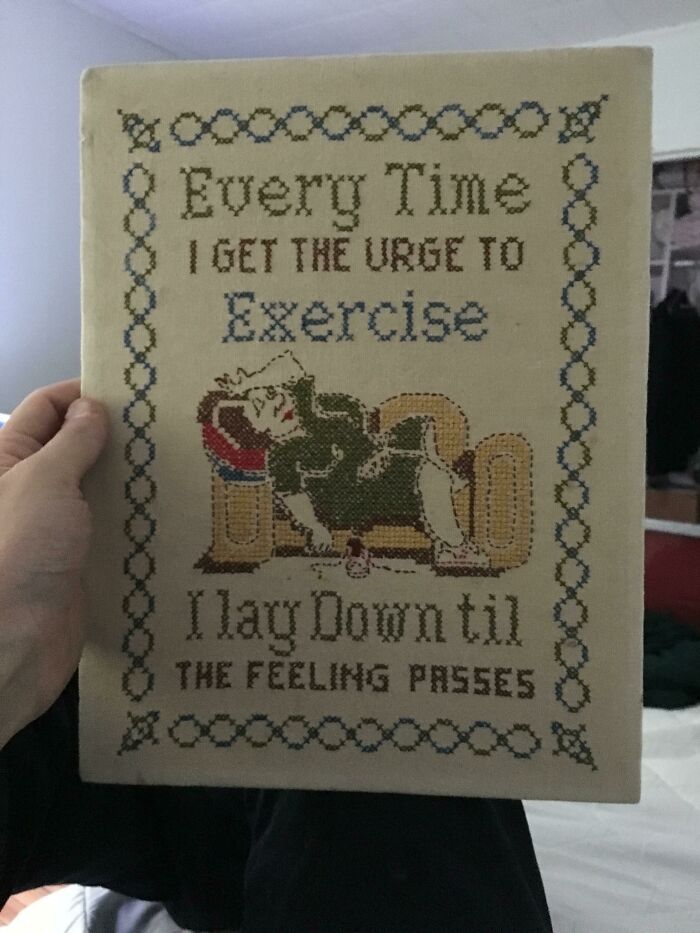 Hand holding a humorous embroidered sign, featuring a relaxed woman and referencing exercise, related to best mothers-in-law.