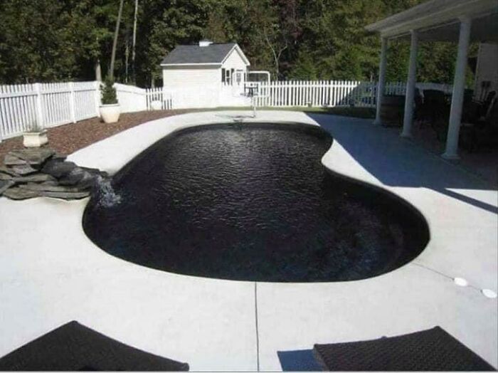 Backyard pool with dark water creating a deep waters effect, triggering thalassophobia in a quiet setting.