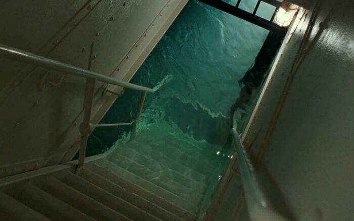 Rusty metal stairs leading down into dark, deep waters, evoking strong feelings related to thalassophobia fear.