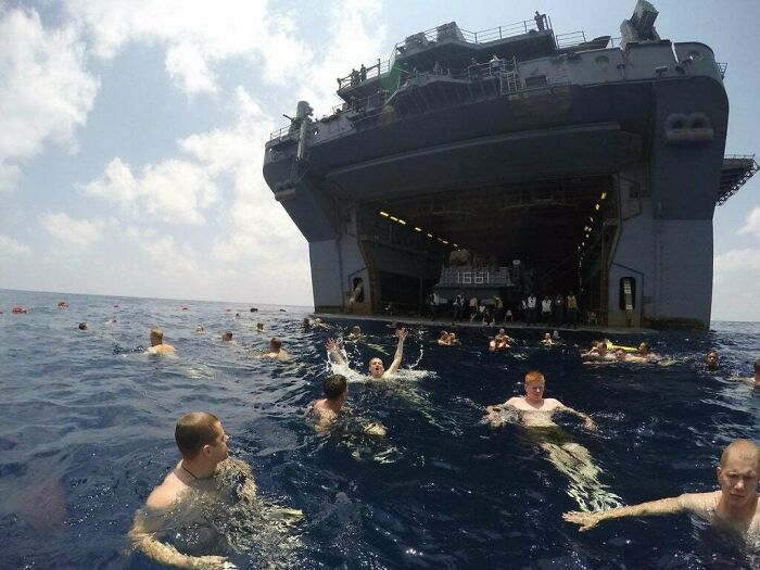 People swimming in deep ocean water near a large ship, illustrating thalassophobia fear of deep waters concept.
