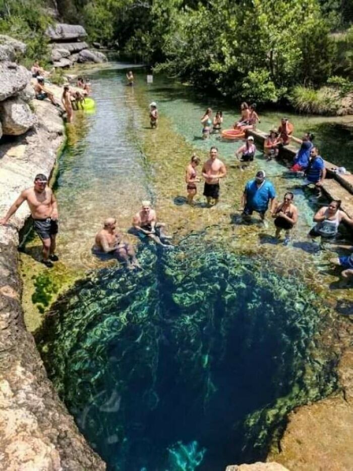 People swimming and standing near an endless deep water hole, triggering thalassophobia and fear of deep waters.