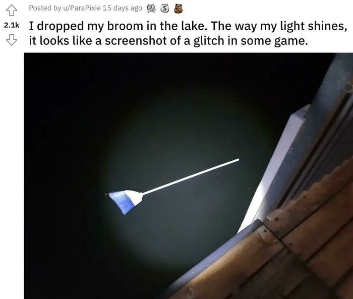 Broom floating in dark lake water lit by a light, creating an eerie effect triggering fear of deep waters.