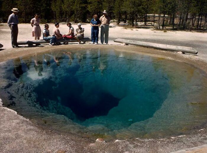 Group of people observing a deep blue natural pool, illustrating a striking example of thalassophobia and fear of deep waters.
