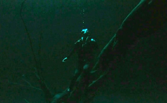 Scuba diver exploring dark underwater environment with eerie deep waters, triggering thalassophobia fears.