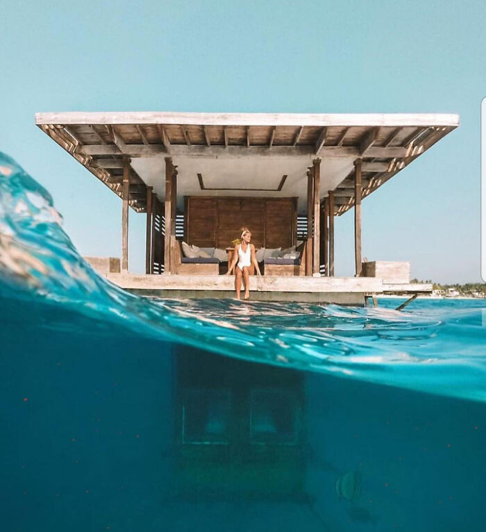 Woman sitting at water's edge with a view of deep waters beneath, illustrating thalassophobia in a serene setting.