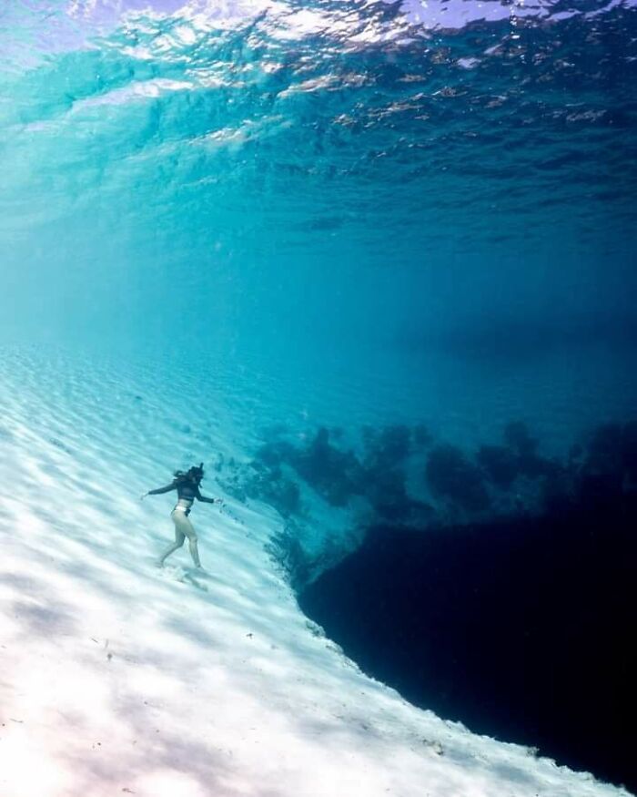 Diver exploring a deep underwater chasm with dark blue waters, capturing the fear of deep waters and thalassophobia.