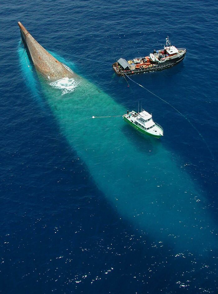 A massive sunken whale beneath the deep water surface near two boats, triggering fear of deep waters.
