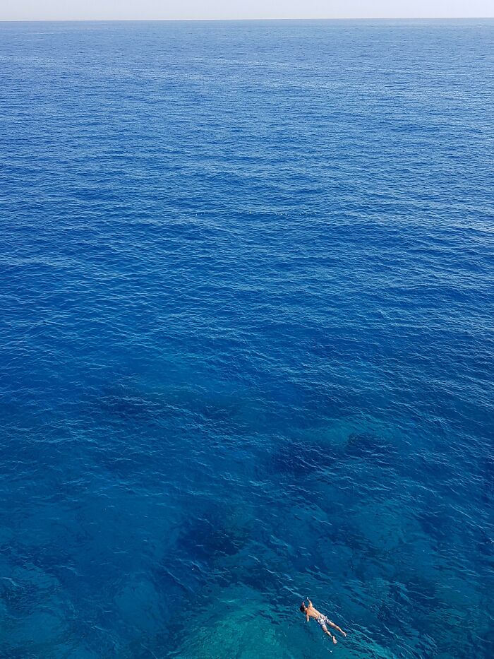 Vast deep blue ocean with a lone swimmer, illustrating the fear of deep waters and triggering thalassophobia.