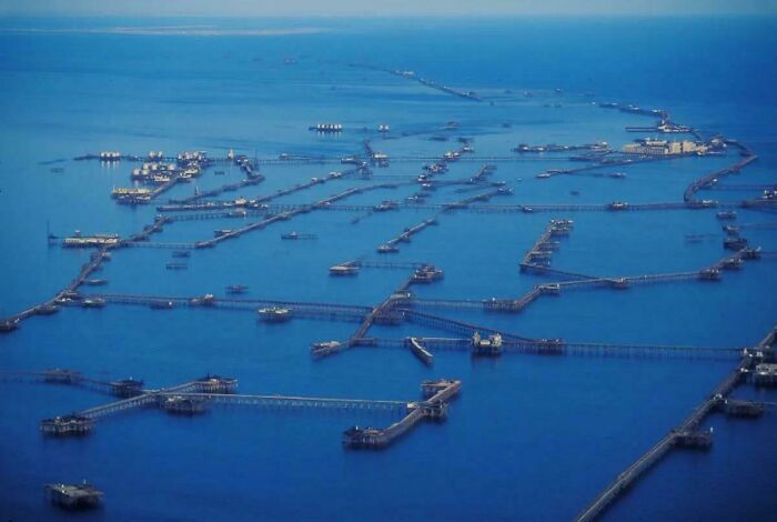 Aerial view of interconnected piers and platforms extending over deep blue waters, evoking thalassophobia feelings.