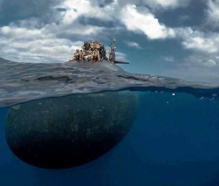 Submarine partially submerged with people on top, surrounded by deep waters triggering thalassophobia fears.