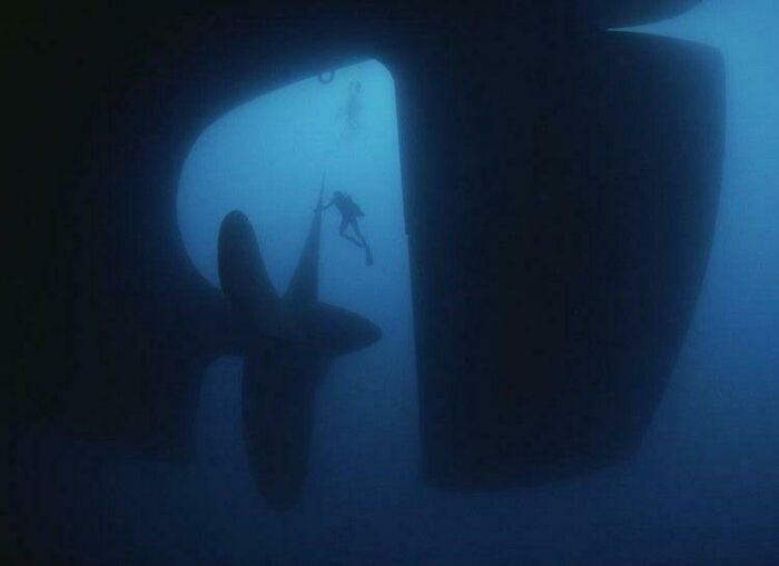 Diver near a massive propeller underwater, illustrating the vast depth to trigger thalassophobia and fear of deep waters.