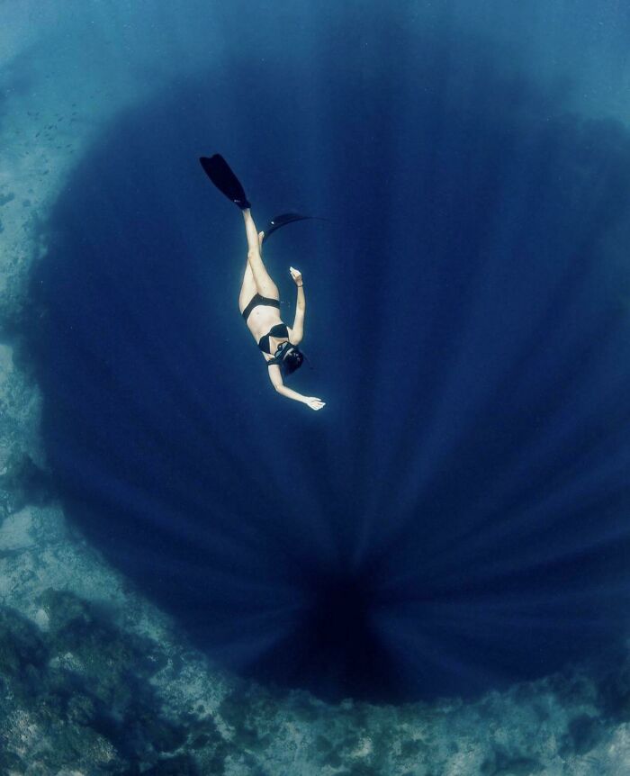 Diver swimming above a deep underwater hole, illustrating the fear of deep waters and thalassophobia.