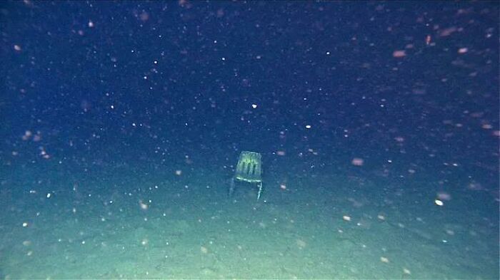 Underwater scene showing a lone chair on the ocean floor, evoking thalassophobia and fear of deep waters.
