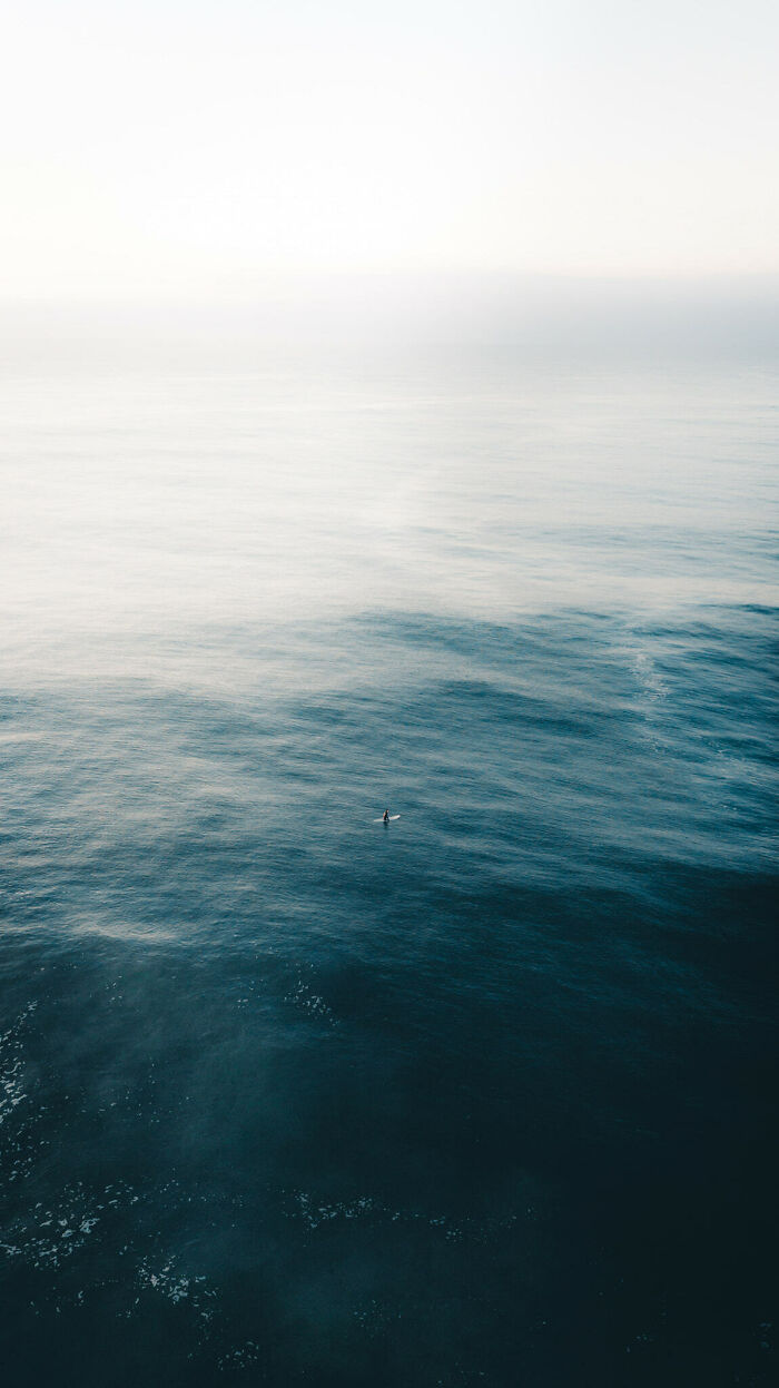 A lone surfer in vast deep waters, capturing the essence of thalassophobia and the fear of open ocean depths.