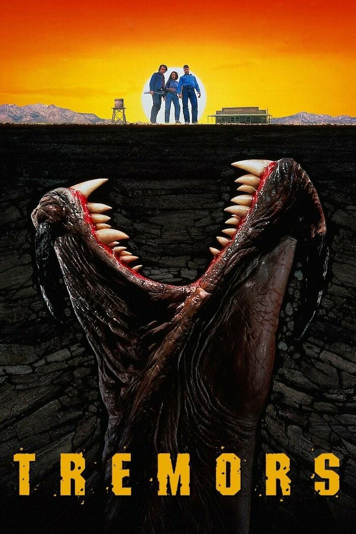 Three people standing on ground at sunset above a giant monster mouth underground in a horror comedy movie scene.