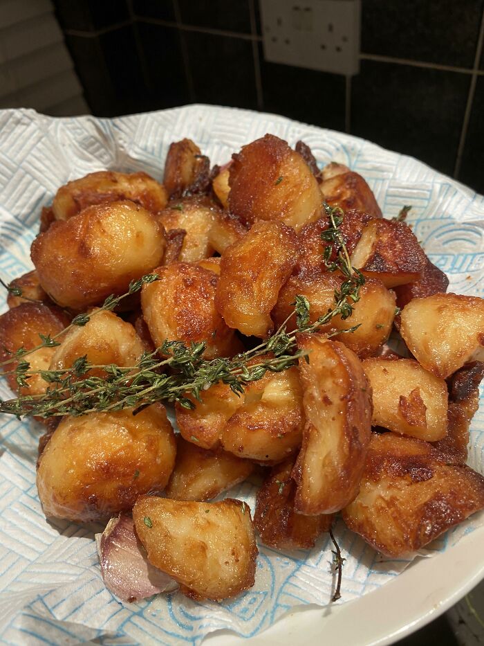 Crispy golden roasted potatoes garnished with fresh herbs, showcasing nearly perfect food presentation in a home kitchen setting.
