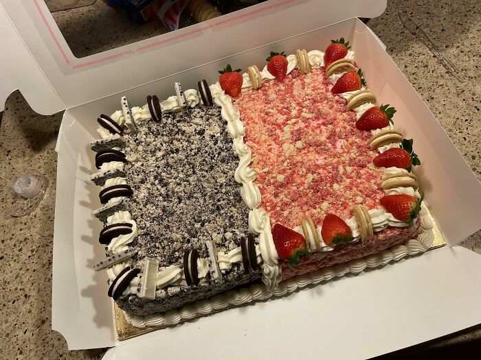 Two-toned rectangular cake with Oreo and strawberry toppings, showcasing nearly perfect food presentation in a white box.