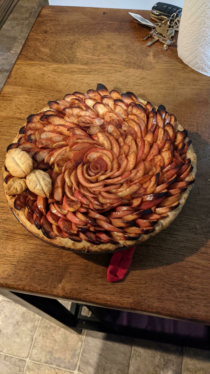 Beautifully arranged nearly perfect apple pie with cinnamon, resembling a rose, on a wooden table surface.