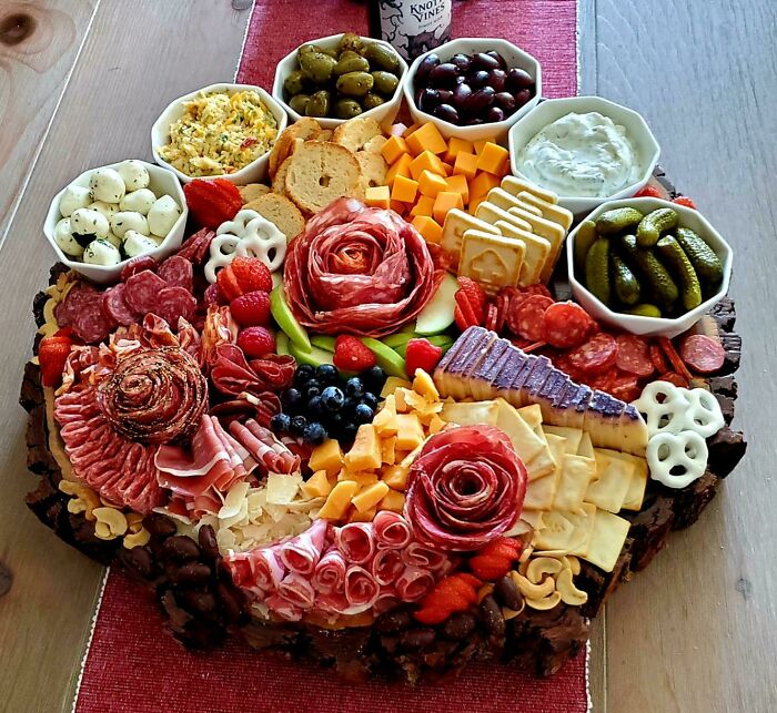 Charcuterie board with nearly perfect food artfully arranged, featuring meats, cheeses, fruits, nuts, and dips.
