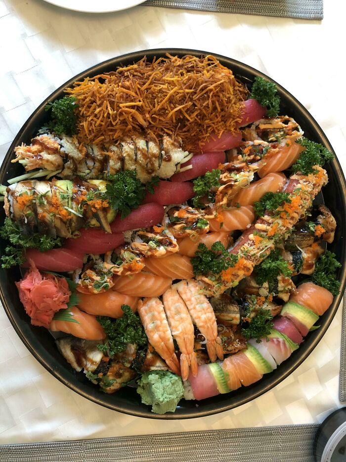 A beautifully arranged platter of nearly perfect sushi with vibrant colors and fresh ingredients, garnished with greens.