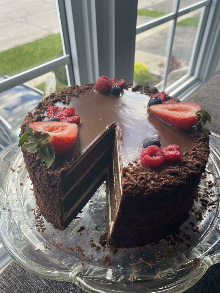 Chocolate layered cake with glossy ganache and fresh berries, showcasing nearly perfect food presentation by people sharing pics.