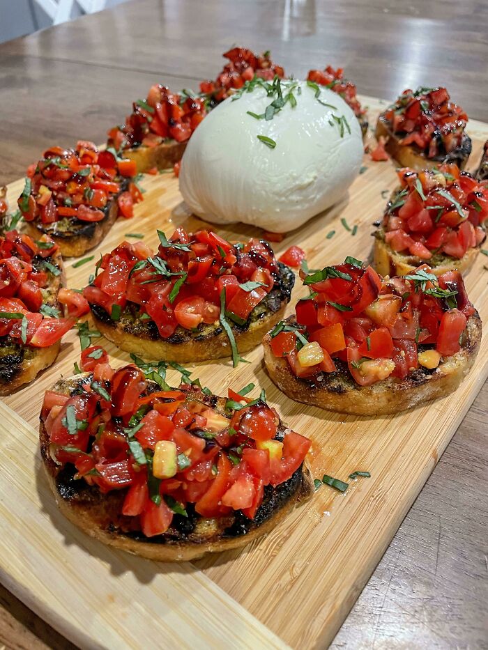 Perfect food presentation with fresh tomato bruschetta and a ball of creamy cheese on a wooden serving board.