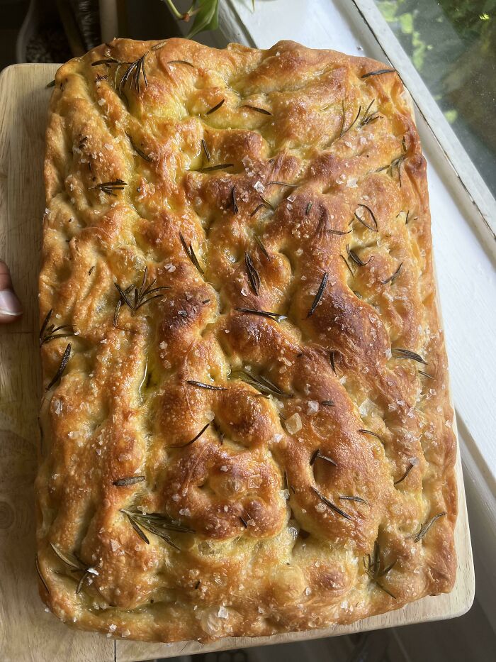 Golden focaccia bread topped with rosemary and sea salt, showcasing nearly perfect food shared by people online.