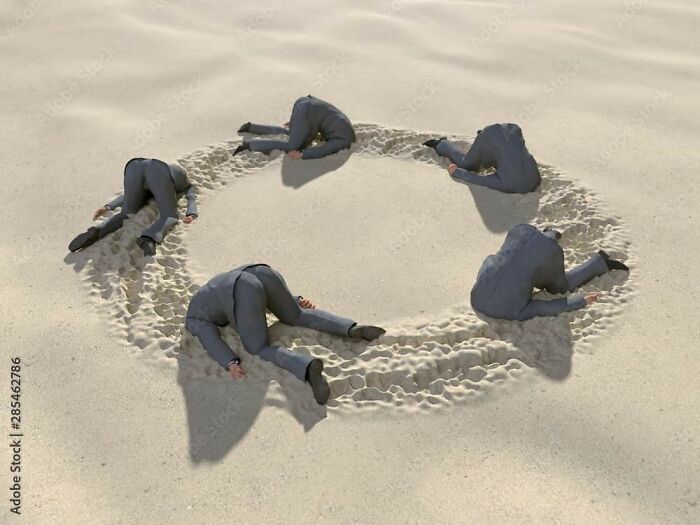 Weird stock image of headless suits arranged in a circle on the sand.