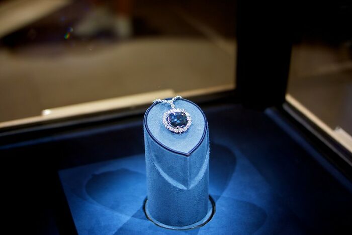 Blue sapphire necklace displayed in a glass case, highlighting one of the big scams many people don’t realize.