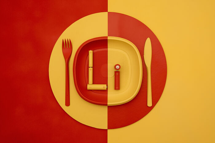 Batteries arranged on a plate with fork and knife, symbolizing environmental problems of the whole Earth on a plate.