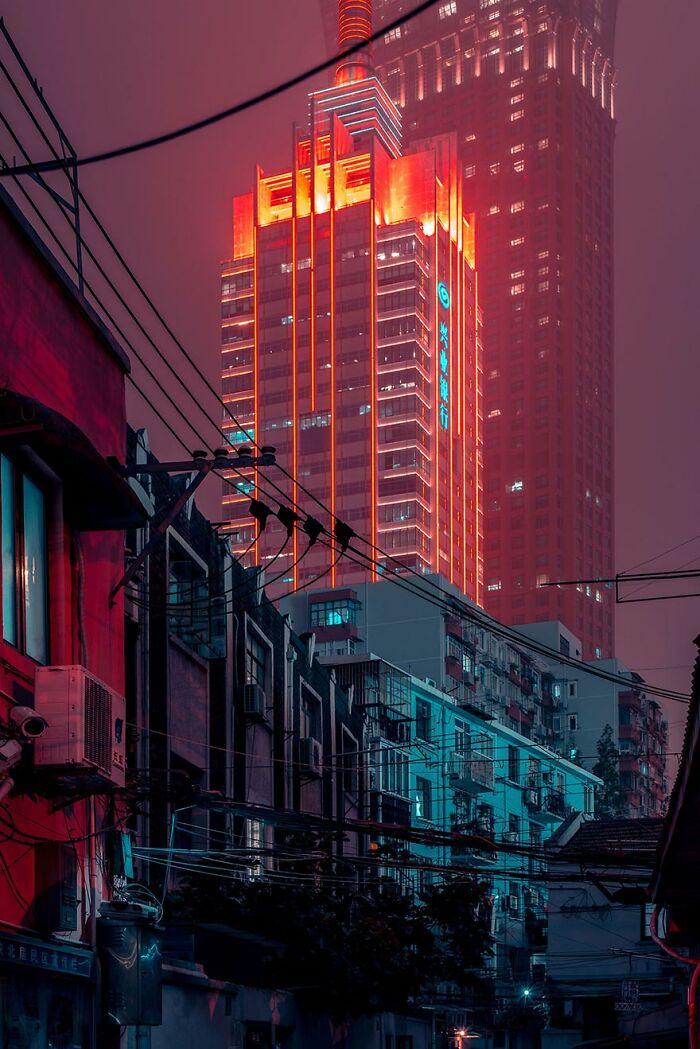 Shikumen lane houses in Shanghai at night with neon-lit modern skyscraper in the background, showcasing urban contrast.