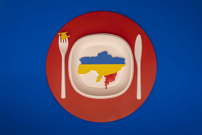 Plate with a map of Earth’s problem with Ukraine in blue, yellow, and red colors, set against a blue background.