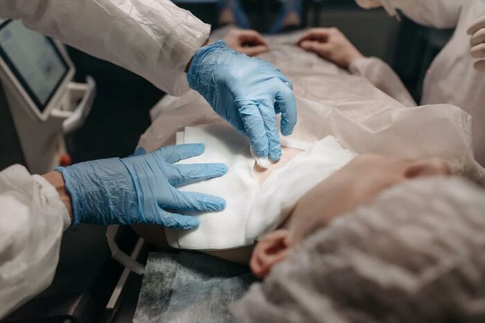 Medical staff wearing blue gloves preparing a patient for surgery, highlighting stories of waking up during surgery.