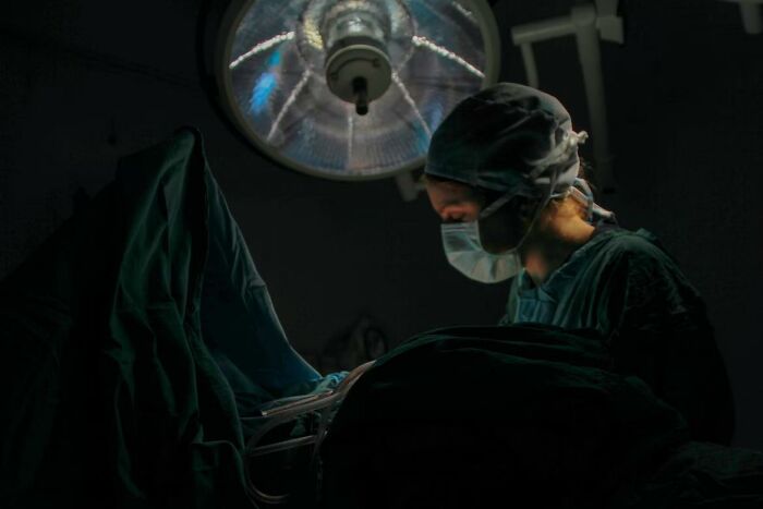 Surgeon in operating room under surgical light, focusing on patient during a bone-chilling surgery experience.