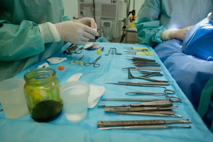 Surgical tools laid out on blue drape with medical staff preparing for bone-chilling surgery stories procedure.