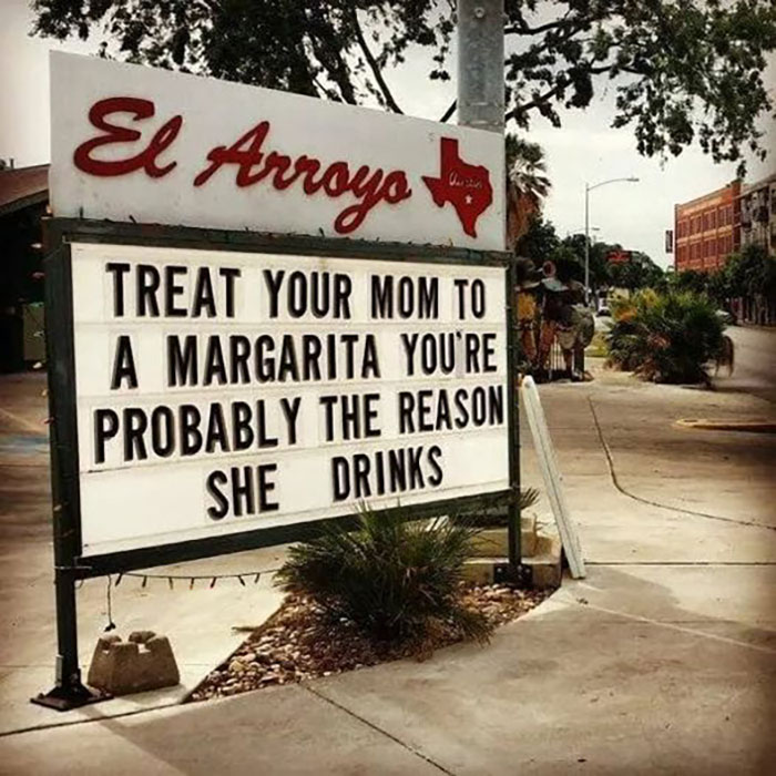 Hilarious and absurd sign outside El Arroyo joking about treating your mom to a margarita because of you.