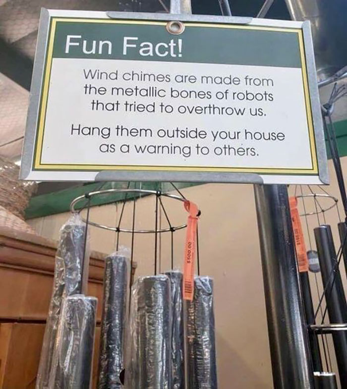 Hilarious and absurd sign claiming wind chimes are made from metallic bones of rebellious robots as a funny warning.