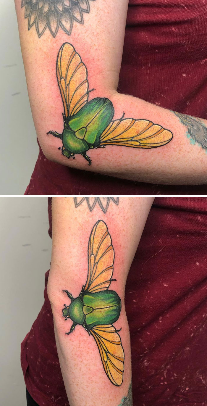 Green beetle tattoo on arm, revealing full wings as arm moves, showcasing genius tattoo design.