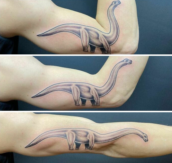 Tattoo of a dinosaur on an arm, changing shape as the arm moves, showcasing a genius tattoo design.