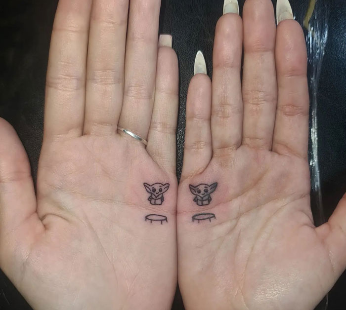 Hands with genius tattoos of small characters above tiny platforms on palms.