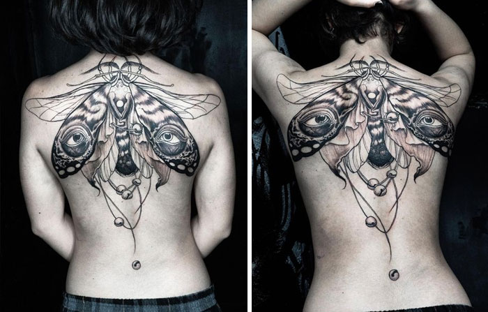Tattoo of a moth with eyes on a woman's back; design transforms with movement.