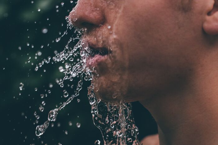 Close-up of a human face with water splashing over skin, highlighting disturbing aspects of human bodies that might freak you out.