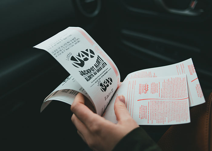 Person holding lottery tickets, symbolizing paths to becoming millionaires.