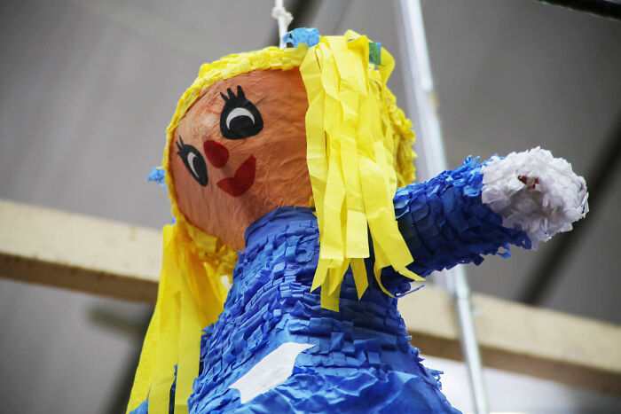 Colorful paper doll piñata with yellow hair and blue dress, symbolizing nightmare wedding guests causing chaos at celebrations.