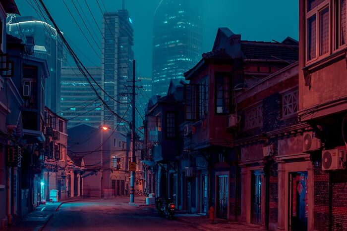 Quiet Shanghai street with historic Shikumen lane houses under glowing city lights at night.