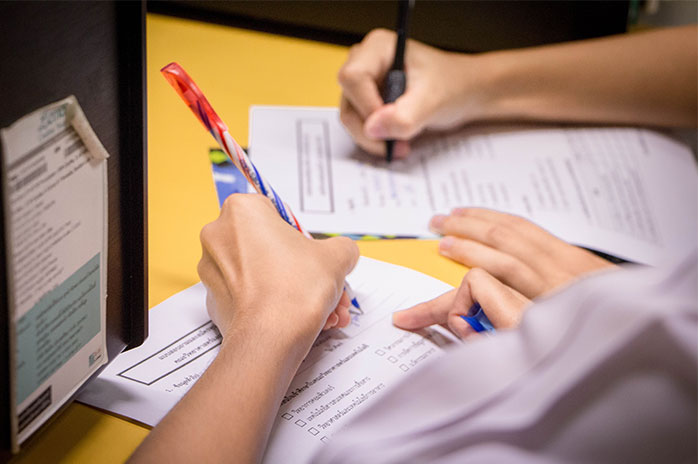 Two people writing a test on a yellow table 