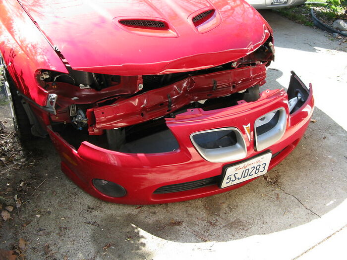 Red car with a damaged front bumper and missing headlights, illustrating startling windshield notes found by folks.